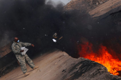 FILE PHOTO: U.S. Air Force personnel toss unserviceable uniform items into a burn pit at Balad Air Base