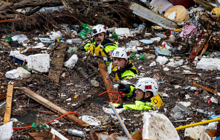 Members of the Tennessee Task Force One search and rescue team wade through the debris-filled Troublesome Creek