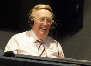 Los Angeles Dodgers announcer Vin Scully smiles in a broadcast booth in Los Angeles
