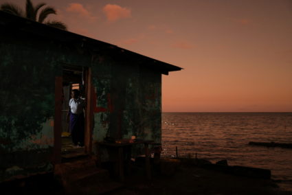 Verina Delasau, 63, moves about inside the home where she lives with family at the edge of the sea, behind a sea wall that no longer protects them from high tides, in Veivatuloa Village, Fiji, July 12, 2022. She has lived in this house for around 20 years. Photo by Loren Elliott/REUTERS