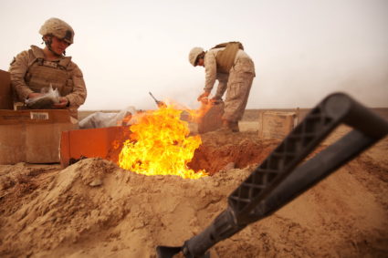 U.S. Marines dispose of trash in a burn pit while stopping for a sandstorm in Afghanistan