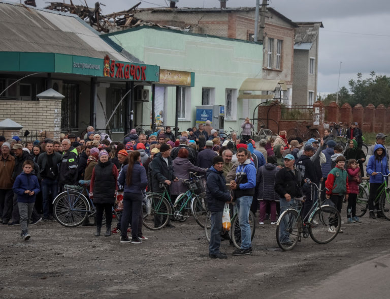 Local residents wait for a car distributing humanitarian aid in the town of Balakliia
