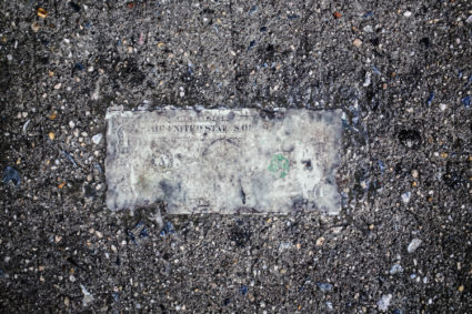 Still life of deteriorating one dollar bill on wet pavement