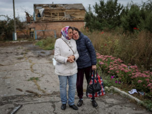 Local residents wait for a car distributing humanitarian aid in the town of Balakliia