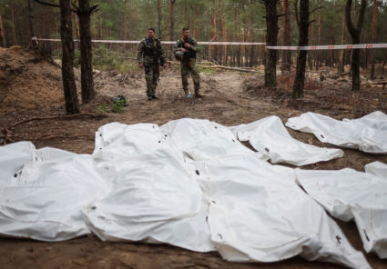 Ukrainian servicemen guard place of mass burial during an exhumation in the town of Izium