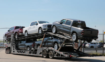 A car hauler transports Dodge Ram pick-up trucks to a holding lot across from the FCA Jefferson North Assembly Plant in De...