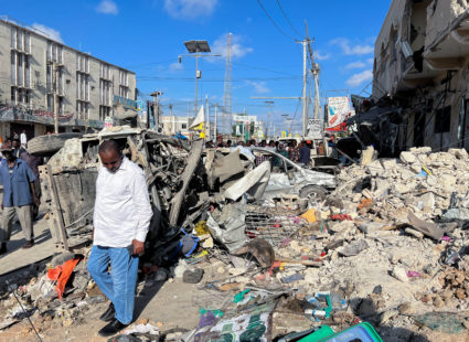A man walks past wreckages of destroyed vehicles near the ruins of a building at the scene of an explosion along K5 street...