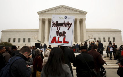 A demonstrator holds a sign aloft as the affirmative action in university admissions case was being heard at the Supreme C...