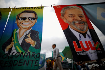 FILE PHOTO: A man walks past presidential campaign materials depicting Brazil's former President Luiz Inacio Lula da Silva...
