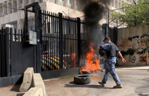 Member of police walks near a burning tyre during a protest near Lebanon's Central Bank building in Beirut