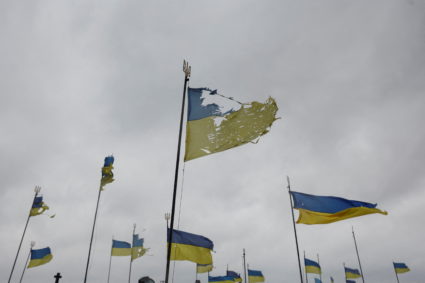 National flags wave over graves of Ukrainian soldiers killed during Joint Forces Operation in the country's eastern regions are seen damaged, as local orthodox priest says, by a shell of Russian tank, as Russia's attack on Ukraine continues, at a cemetery in Chernihiv, Ukraine April 6, 2022. Photo by Serhii Nuzhnenko/REUTERS