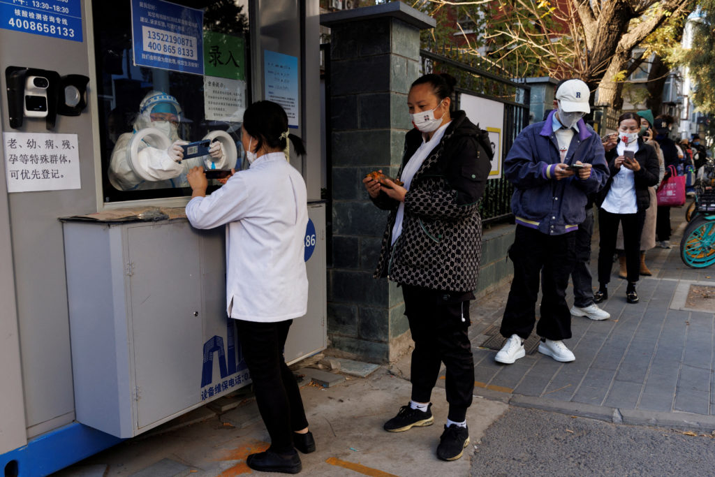 FILE PHOTO: People line up to register their personal details before getting a swab test at a testing booth, as outbreak o...