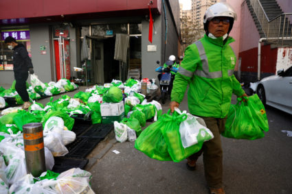 FILE PHOTO: Delivery workers pick up goods of online grocery platform by Meituan in Beijing