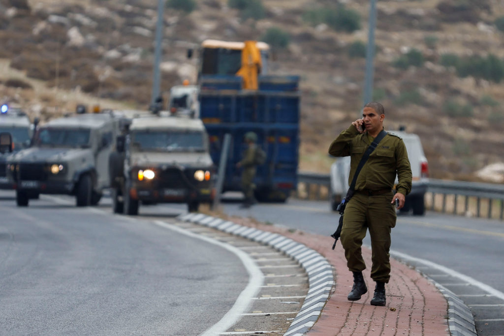An Israeli soldier speaks on a phone at the scene of an incident, in the Israeli-occupied West Bank, November 29, 2022. Ph...