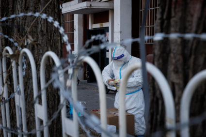 A pandemic control worker in a protective suit works in a partially locked-down residential compound as outbreaks of the c...