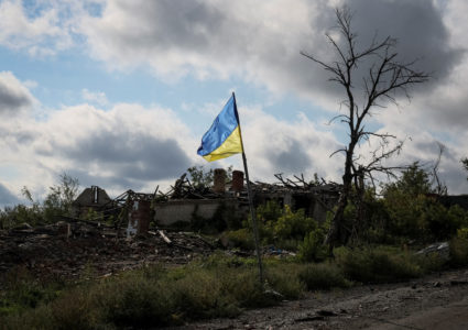 Ukrainian national flag is seen near destroyed buildings in the village of Dolyna