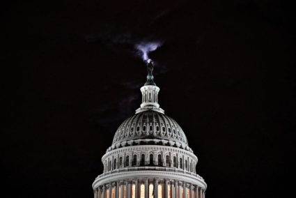 FILE PHOTO: The moon is seen behind the dome of the U.S. Capitol building at night in Washington