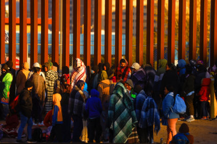 Migrants queue near the border fence after crossing the Rio Bravo river, in Ciudad Juarez