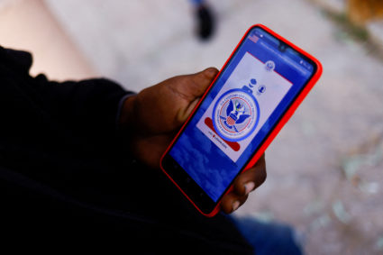 FILE PHOTO: Migrants seeking asylum in the U.S. use their phones to request an appointment at a land port of entry to the ...