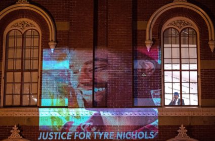 A security guard looks out of a window as protesters project an image of Tyre Nichols during a Jan. 27, 2023 rally in Washington, D.C., against the fatal assault of Nichols by Memphis police. Photo by Andrew Caballero-Reynolds/AFP via Getty Images