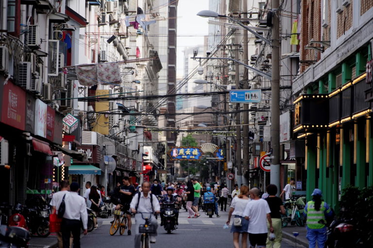 People walk and ride vehicles along a street, amid the coronavirus disease pandemic, in Shanghai