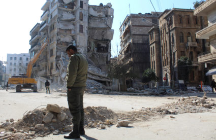 A man stands near damaged buildings, in the aftermath of a deadly earthquake, in Aleppo