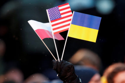 A man holds Ukrainian, Polish and U.S. flags before U.S. President Joe Biden addresses the public during an event outside the Royal Castle, in Warsaw, Poland, February 21, 2023. Photo by David W Cerny/REUTERS