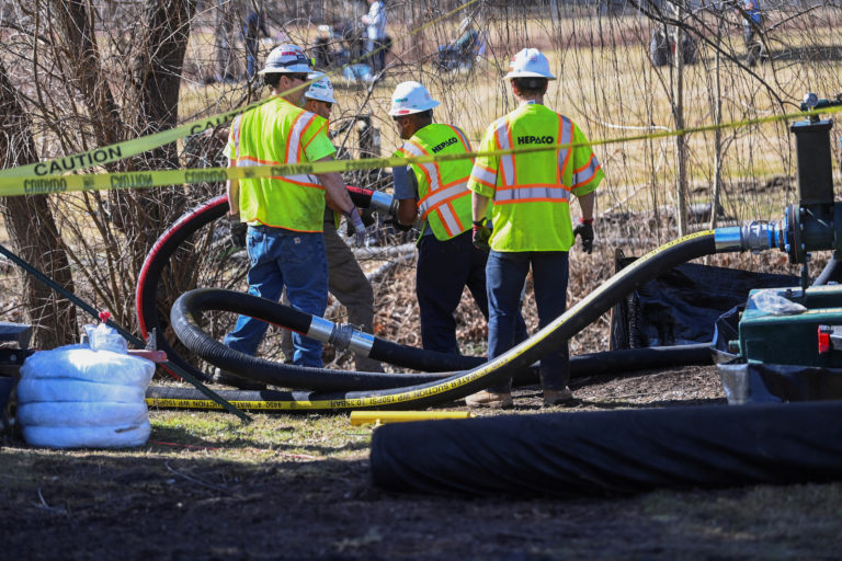People clean up the site following the derailment of a train carrying hazardous waste in East Palestine, Ohio