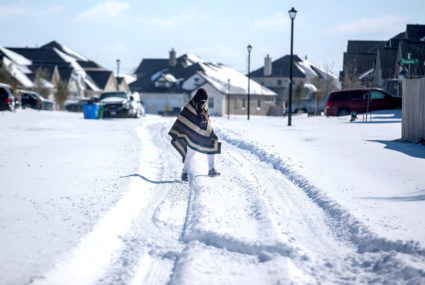 FILE PHOTO: A man walks to his friend's home in a neighbourhood without electricity as snow covers the BlackHawk neighborh...