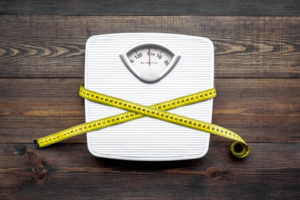 Lose weight concept. Scale and measuring tape on dark wooden background top view