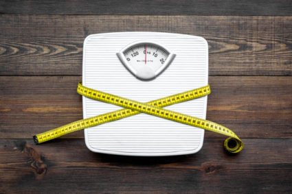 Lose weight concept. Scale and measuring tape on dark wooden background top view
