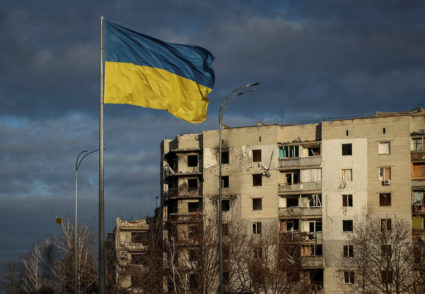 Ukrainian national flag flies near buildings destroyed by Russian military strike in Borodianka