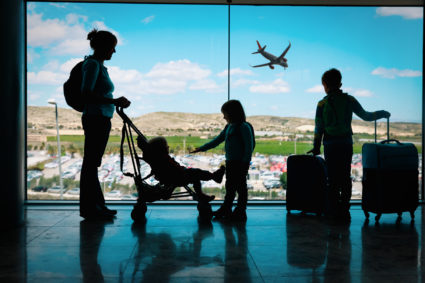 mother with kids and luggage looking at planes in airport. File photo provided by Getty Images