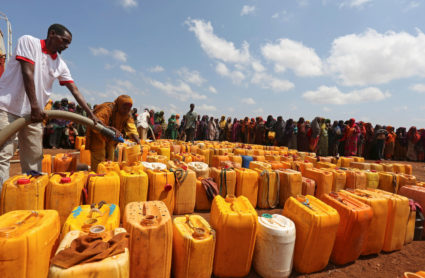 Internally displaced Somali women gather with their jerrycans to receive water at a distribution centre organized by a Qat...