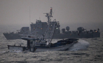 Fishing boat sails past a South Korean navy ship patrolling off Yeonpyeong Island