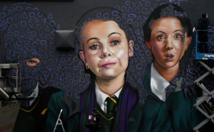 A camera operator films as graffiti artist spray paints a new mural of 'Derry Girls' television show in Londonderry