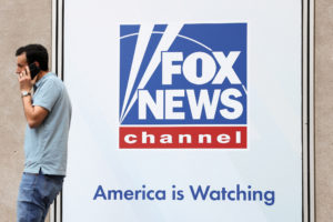FILE PHOTO: A person walks by Fox News signage posted on the News Corporation building in New York City