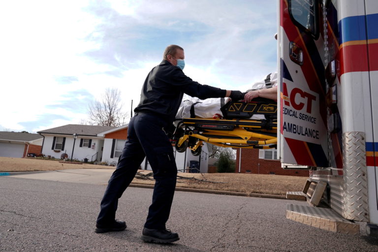A paramedic loads a woman with coronavirus disease (COVID-19) into an ambulance, in Shawnee