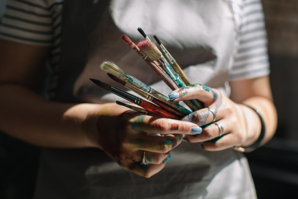 Midsection Of Woman Holding Paintbrushes