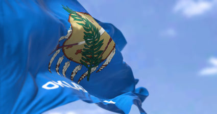 The US state flag of Oklahoma waving in the wind. Oklahoma is a state in the South Central region of the United States