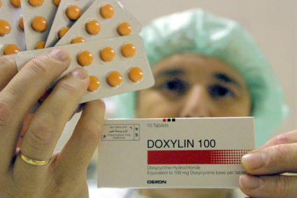 A worker at the Dexxon pharmaceuticals plant holds up a package of their Doxylin antibiotics drug November 8, 2001 in the Israeli town of Or Akiva. Photo by David Silverman/Getty Images