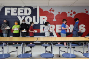 Older students carry their lunches to their classrooms to eat, leaving the lunchroom free for younger students to keep a s...