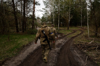 Ukrainian service members walk at a position in direction of the border with Belarus in Kyiv region