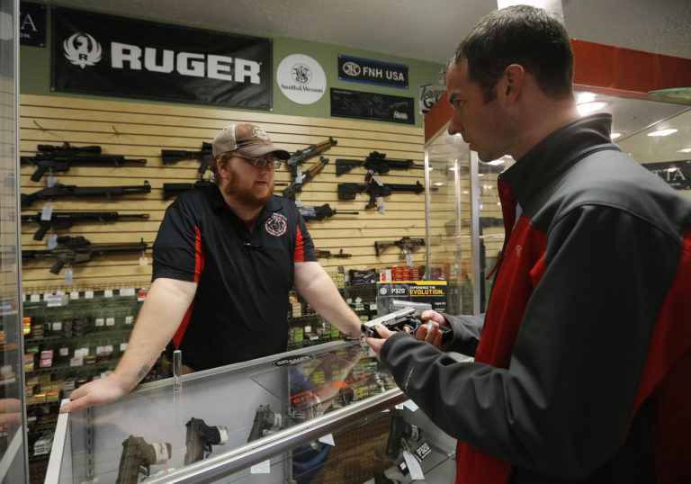 Metro Shooting Supplies' employee Chris Cox speaks to Steve Christy about the purchase of a 9mm handgun in Bridgeton