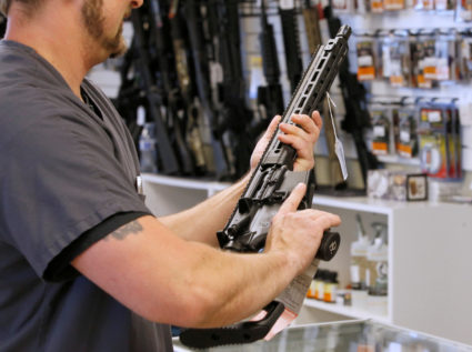 A prospective buyer examines an AR-15 at the "Ready Gunner" gun store