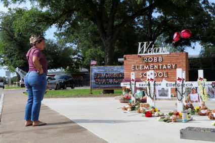 A woman brings flowers to a memorial for the victims of a school shooting at Robb Elementary School in Uvalde