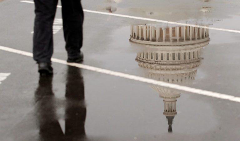 FILE PHOTO: The dome of the U.S. Capitol Building is reflected in a puddle on a rainy morning in Washington