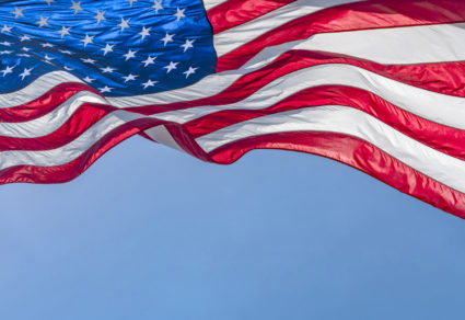 Low angle view of American flag waving in wind against clear sky