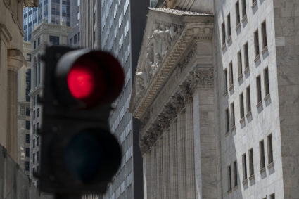 A red traffic light is seen in front of a general view of the New York Stock Exchange on Wall Street in New York City.