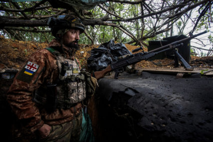 Ukrainian serviceman observes an area from a trench at a position near the frontline town of Bakhmut